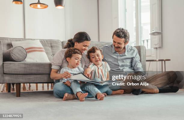 family reading a book - family lockdown stock pictures, royalty-free photos & images