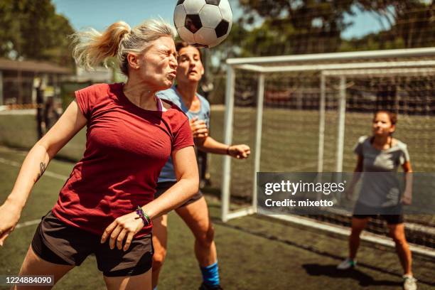 female soccer striker heads ball into the goal - soccer scoring stock pictures, royalty-free photos & images