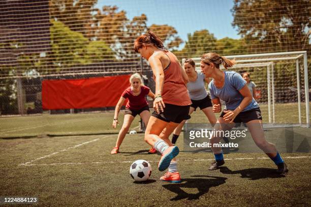 femmes adultes moyennes jouant au football sur le terrain - tackling photos et images de collection