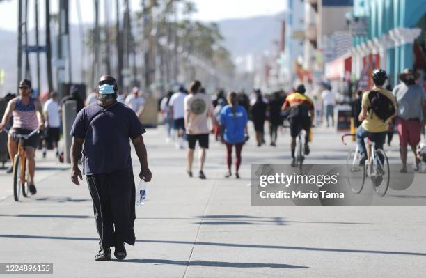 Man wears a face mask along the Venice Beach boardwalk on the day Los Angeles County reopened its beaches, which had been closed due the coronavirus...