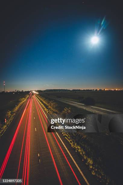 slow shutter of cars lights on highway with full moon. - slow shutter stock pictures, royalty-free photos & images