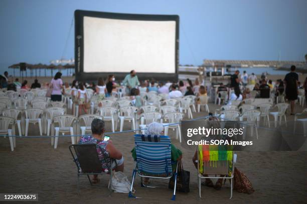 Women are seen sitting on beach chairs as they wait for a movie at La Malagueta beach amid coronavirus outbreaks. During the summer season, the event...