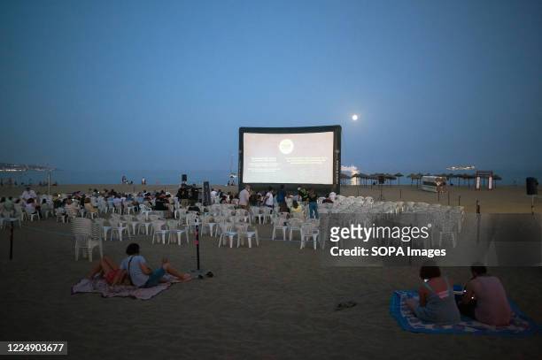 People are seen watching a movie at La Malagueta beach amid coronavirus outbreaks. During the summer season, the event 'Open cinema' welcomes free...