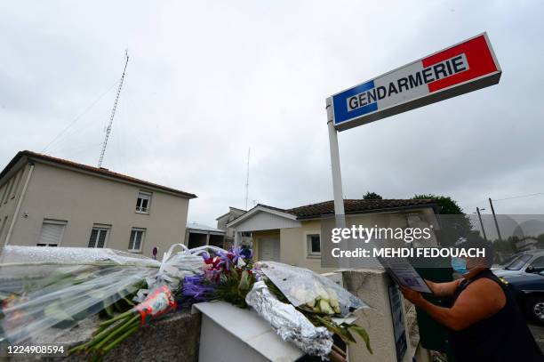 Man writes in a tribute book next to flowers and messages displayed on July 6, 2020 at the Gendarmerie in L'Aiguillon, southwestern France, in memory...