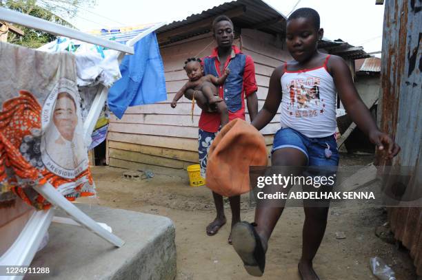 Girl plays ball on January 23, 2012 next to laundry with a portrait of Equatorial Guinean President Teodoro Obiang Nguema drying outside a home in...