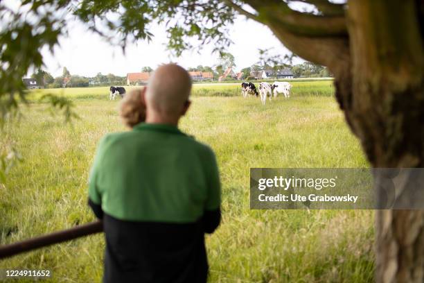 In this photo illustration a man with a child are looking at some cows on June 20, 2020 in Oostkapelle, Netherlands.