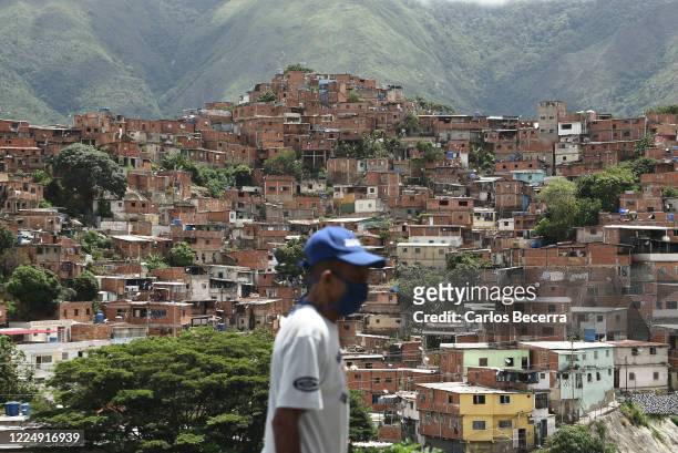 Man wearing a face mask walks in front of the Petare slum on July 6, 2020 in Caracas, Venezuela. Venezuela resumes today a total lockdown after a...