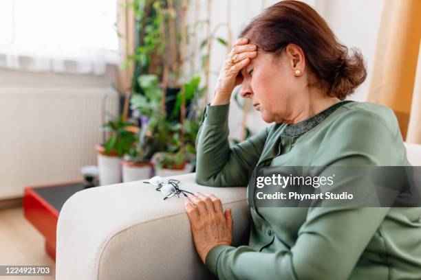 a distraught senior woman suffering from a migraine - serious illness stock pictures, royalty-free photos & images