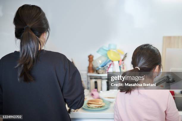 mother and daughter making hot cake - girls hands behind back stock-fotos und bilder