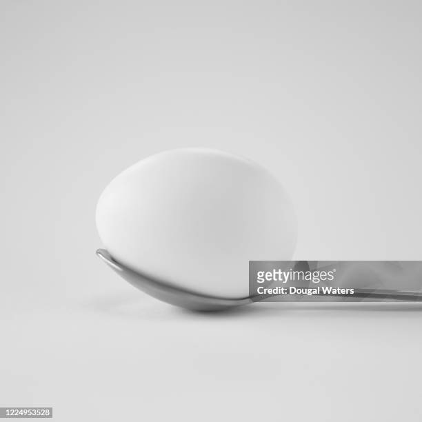 white chicken egg on metal spoon against white background, close up. - perfect fit ストックフォトと画像