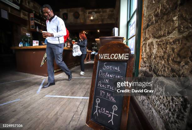 Customers walk past a social distancing sign after buying their beers at the Hero of Waterloo pub in The Rocks on May 15, 2020 in Sydney, Australia....