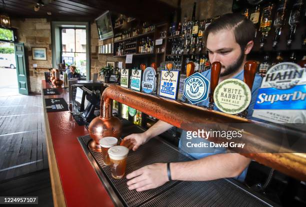 Barman pours beers from taps for customers at the Hero of Waterloo pub in The Rocks on May 15, 2020 in Sydney, Australia. Restrictions put in place...