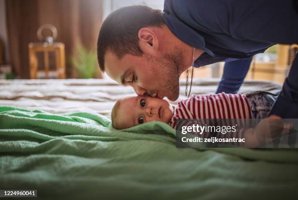 happy   young family laying on bed in bedroom with baby - leanincollection mother stock pictures, royalty-free photos & images