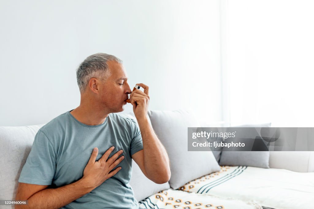 Hombre maduro usando inhalador de asma