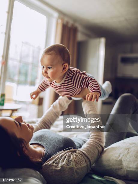 happy   young family laying on bed in bedroom with baby - happy newborn stock pictures, royalty-free photos & images