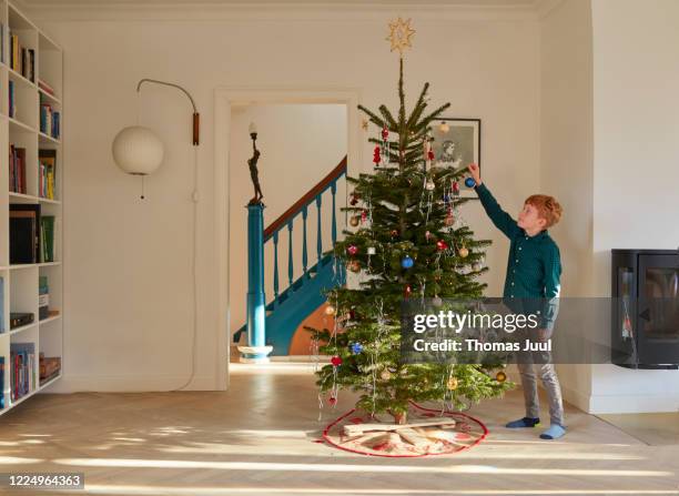 boy decorating christmas tree at home - 10 11 jaar stockfoto's en -beelden