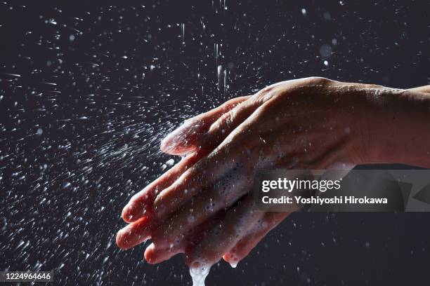 close-up of person washing hands against black background - chofu stock-fotos und bilder