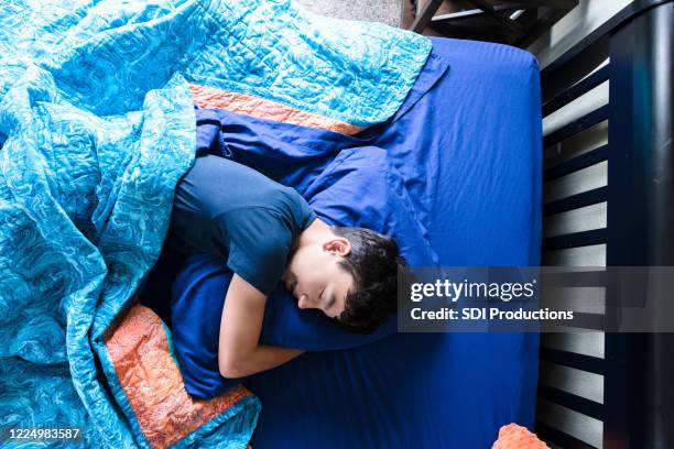high angle view teen boy hugging pillow while sleeping - boy sleeping stock pictures, royalty-free photos & images