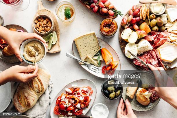 テーブルの上に新鮮な地中海の盛り合わせを食べる女性 - パン　持つ　手　女性 ストックフォトと画像