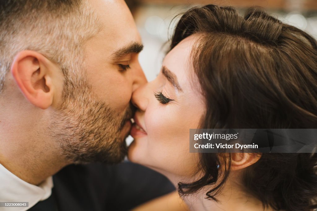 The groom kisses the bride in the nose in the bar