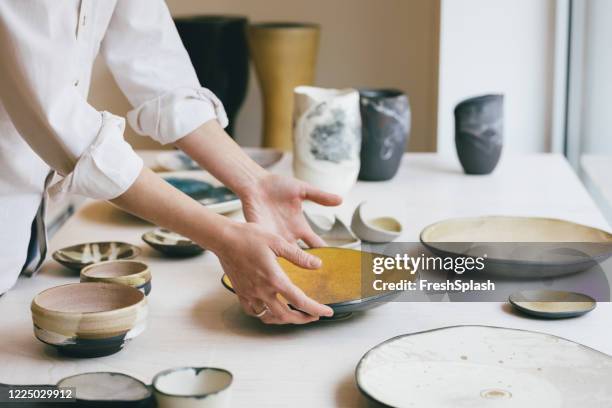 cearamic dishware in der galerie, eine handgefertigte platte in ein schaufenster gelegt - pottery stock-fotos und bilder