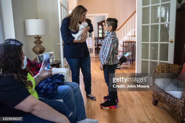 Elementary school teacher Luciana Lira kisses baby Neysel, six weeks, in her home after introducing him to his brother Junior first time on May 14,...