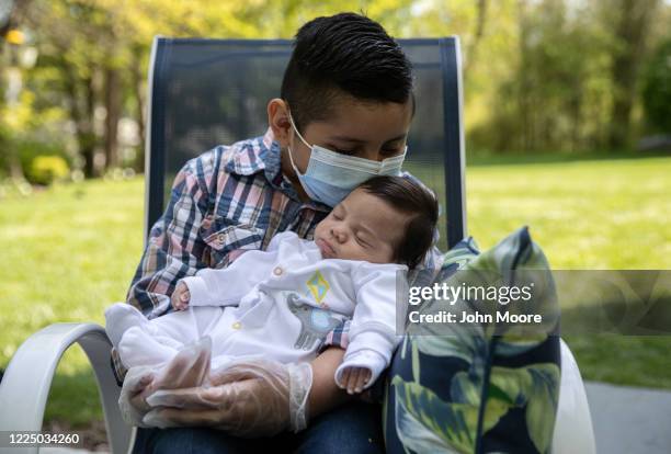 Junior holds his baby brother Neysel, six weeks, for the first time on May 14, 2020 in Stamford, Connecticut. Junior and his family, now all testing...