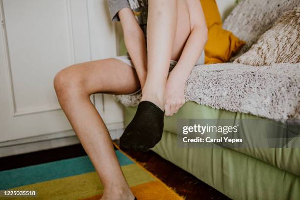 low section  male teenager putting socks on - male feet fotografías e imágenes de stock