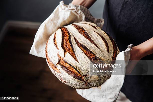 焼きたてのサワードウパンを持つ女性 - loaf of bread ストックフォトと画像