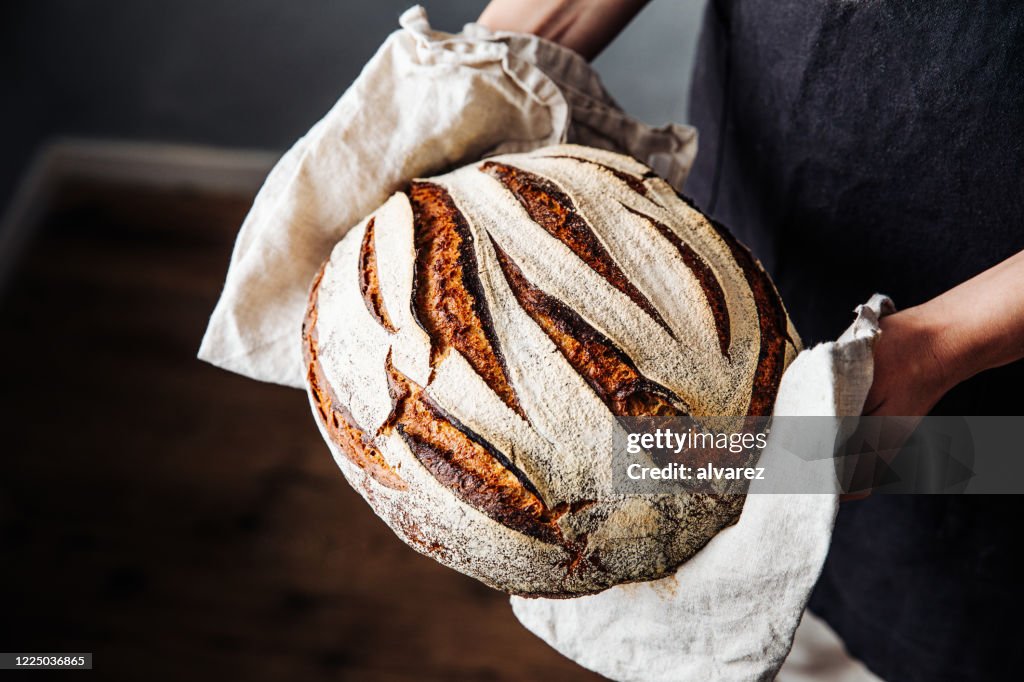 Woman holding fresh baked sourdough bread