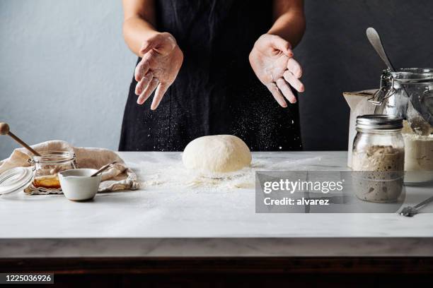 donna che getta pasta sulla farina sul bancone di marmo - pane a lievito naturale foto e immagini stock