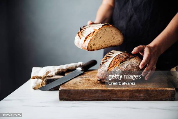 kvinna håller bröd på skärbräda i köket - loaf of bread bildbanksfoton och bilder