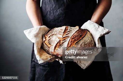 Vrouw met vers gebakken zuurdesembrood in keuken Vrouw met vers gebakken zuurdesembrood in keuken