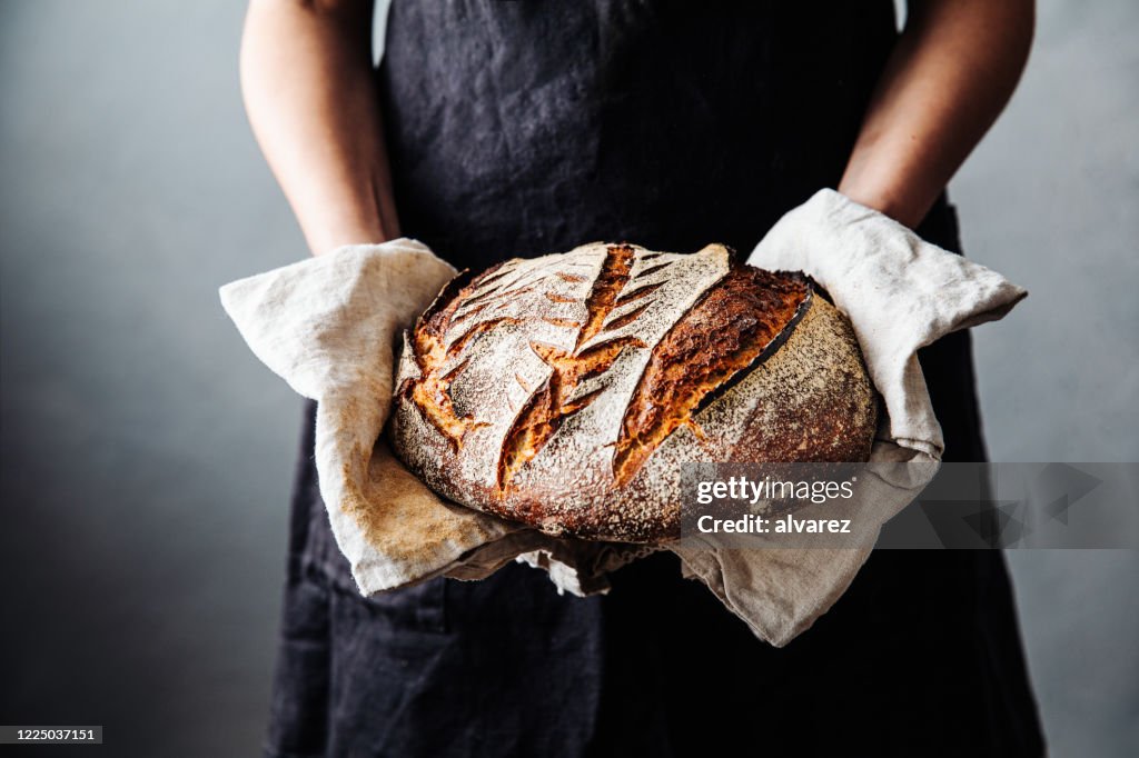 Mulher com pão assado fresco na cozinha