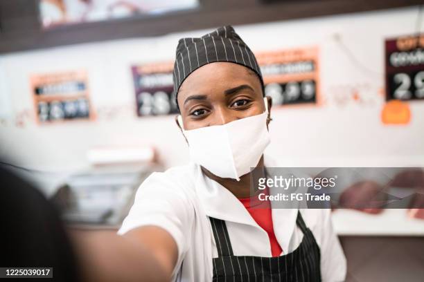 carnicero femenino tomando un selfie en la carnicería - con máscara facial - servizio fotografico fotografías e imágenes de stock