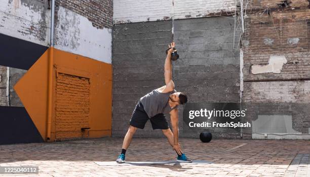 kracht workout: een fit man oefenen met een kettlebell buiten - kettlebell stockfoto's en -beelden