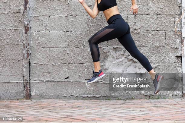 fit woman in black sportswear running outdoors - legging stock pictures, royalty-free photos & images