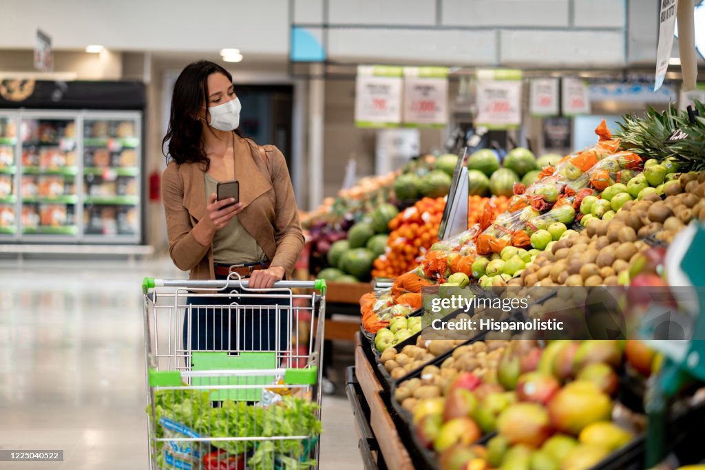 穿著面罩在雜貨店購物的女人