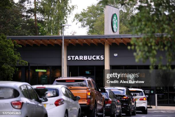 General view as customers queue in their cars outside a Starbucks drive-through on the day after it's re-opening on May 15, 2020 in Fleet, England....