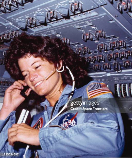 American astronaut and physicist Sally Ride , holding a tape recorder, communicates with ground controllers from the flight deck of Space Shuttle...