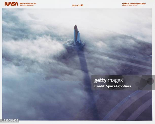 The Space Shuttle Challenger, atop a mobile launch platform, slowly moves through Florida fog to Launch PAd 39A in preparation for its first liftoff,...