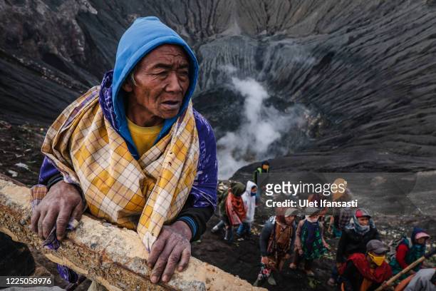Villagers stand as wait to catch offering thrown by Tenggerese worshippers during the Yadnya Kasada Festival at crater of Mount Bromo amid the...