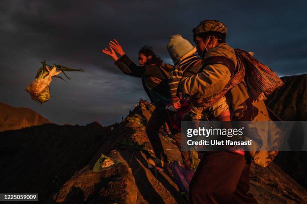Tenggerese worshipper throw vegetables as offerings during the Yadnya Kasada Festival at crater of Mount Bromo amid the coronavirus pandemic on July...