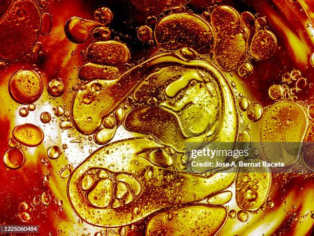 full frame of abstract shapes and textures formed of bubbles and drops on a gold colored liquid background. - oil splashing stock pictures, royalty-free photos & images