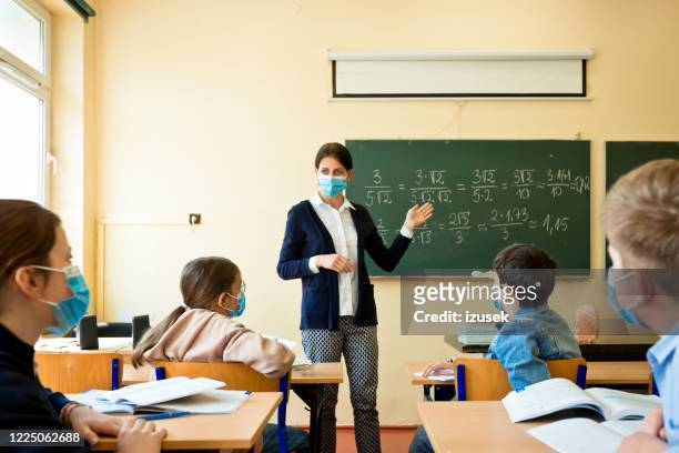 covid-19. ein lehrer unterrichtet mathematik - teacher stock-fotos und bilder