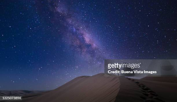 woman climbing sand dune at night - three quarter length stockfoto's en -beelden
