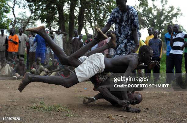 South Sudanese members of the Mundari ethnic group wrestle in a dusty patch where the tribe brought cattle and sheep for sale in Juba on July 7, 2011...