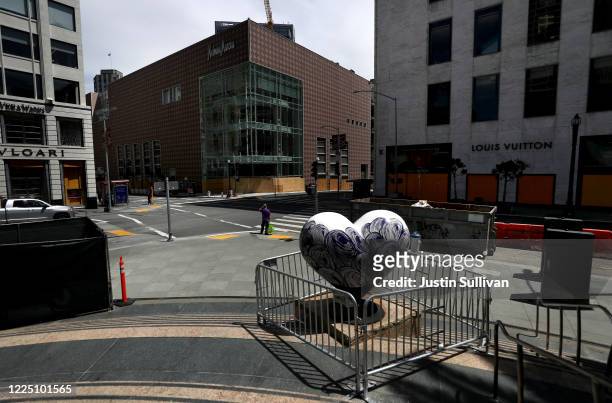 Pedestrian waits to cross the street near boarded up businesses on May 15, 2020 in San Francisco, California. Malls and other businesses shutdown in...