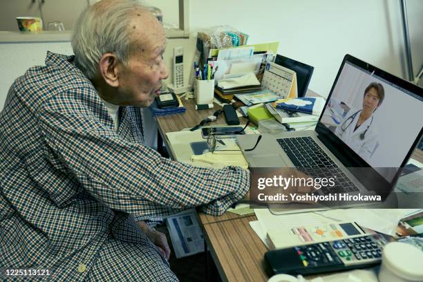 senior use laptop for remote medical treatment with doctor at home - centenaire et plus photos et images de collection