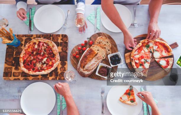 family or friends sitting at dining table set with take away food. - heart shape pizza stock pictures, royalty-free photos & images